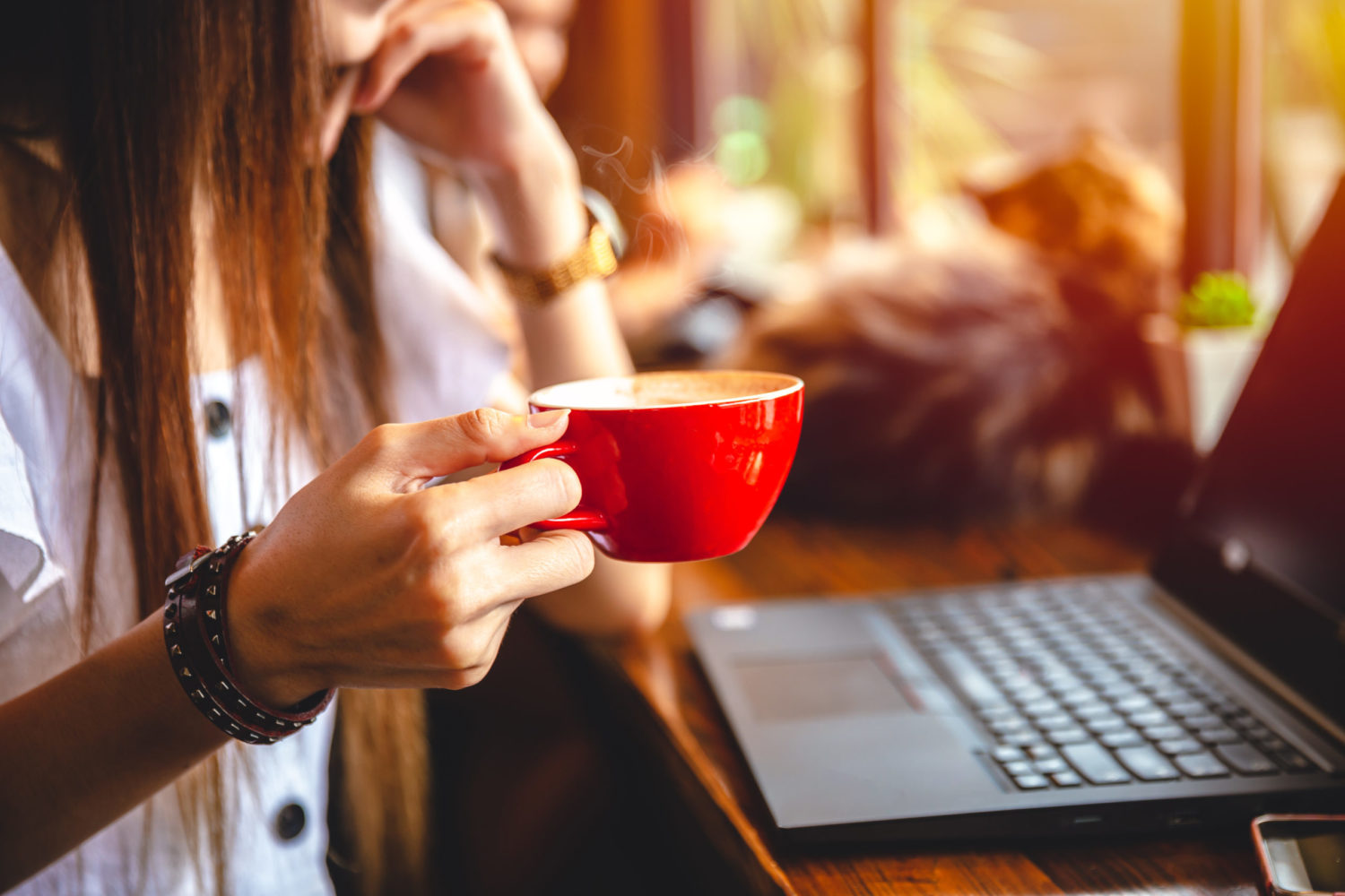 Freelace businesswoman hand holding coffee mug working with laptop computer on wooden table for business cafe hopper lifestyle.